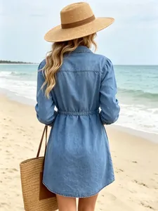 Back view of a casual waist-tie denim dress styled with a straw hat on the beach