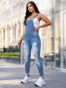 Detail view of distressed denim overalls with ripped knees and slim fit for women