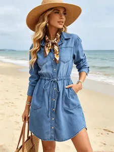 Detailed view of a casual blue denim shirtdress with drawstring waist at beach