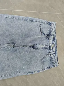 Close-up of light blue high-waist denim jeans featuring sparkling rhinestone embellishments