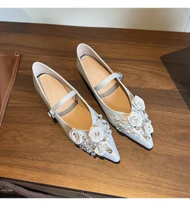 Detailed view of pointed-toe Mary Janes with fabric roses and clear crystal accents.