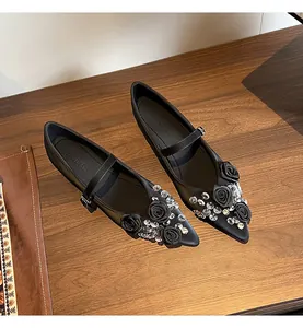 Detailed view of black pointed-toe Mary Jane shoes with rose and crystal accents.