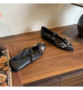 Detail of black pointed-toe Mary Janes with rose and crystal embellishments.