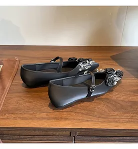 Detailed side view of black pointed toe Mary Jane flats with rose and rhinestone accents