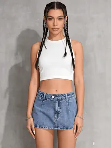 Front view of woman wearing a vintage washed denim mini skort and white ribbed crop top