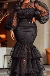 Detail view of black flocked polka dot dress with sheer puff sleeves and tiered mermaid hem