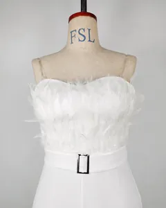 Detailed macro view of white strapless jumpsuit with fluffy feather trim and waist belt buckle