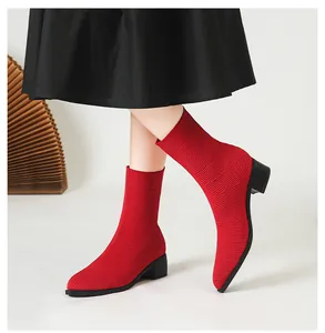 Primer plano de botines tipo calcetín de punto rojo con punta afilada y tacón grueso