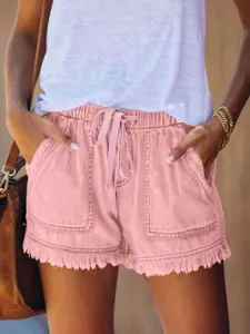 Dettaglio di pantaloncini di jeans rosa a vita alta con elastico e orlo a frange.