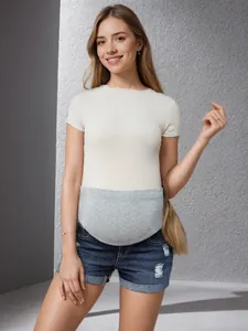 Détail d'un short en jean de maternité avec un bandeau de grossesse gris pour plus de confort.