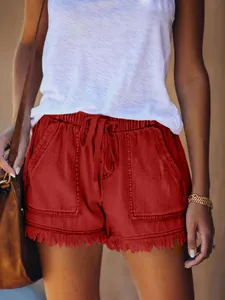 Dettaglio degli shorts di jeans rossi a vita alta con vita elastica e orlo con frange