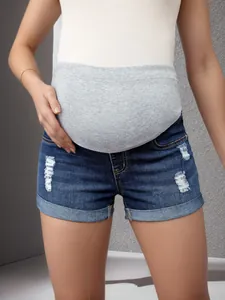 Short de maternité en jean usé avec un bandeau de maintien gris doux sur le ventre.