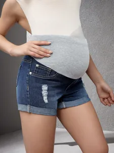 Vue détaillée du short en jean de maternité montrant le bandeau élastique et le tissu délavé.