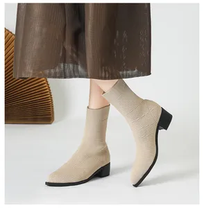 Primer plano de botines de punto beige con punta afilada y una textura acanalada.