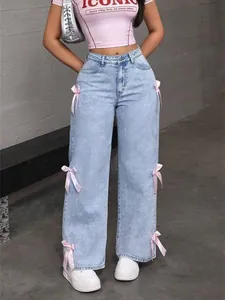 Detailed view of high waisted light blue wide-leg jeans featuring cute pink bow accents