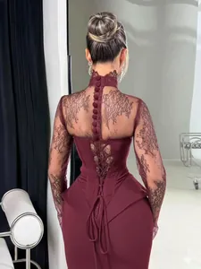 Détail d'une robe moulante bordeaux avec manches en dentelle et dos lacé style corset.