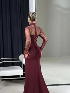 Détail du dos lacé d'une robe sirène bordeaux avec manches élégantes en dentelle.