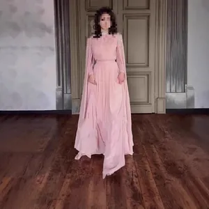 Elegante lichtroze vloerlange jurk met kralen cape mouwen en een hoge halslijn.