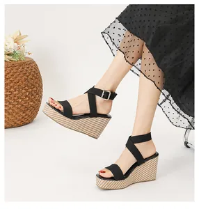 Primer plano de elegantes sandalias con cuña negra y plataforma de paja tejida