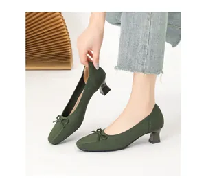 Dettaglio di décolleté in maglia verde scuro con punta quadrata, fiocco e tacco