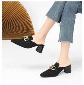 Detailansicht stilvoller schwarzer Strick-Mules mit Goldkette und stabilem Blockabsatz.