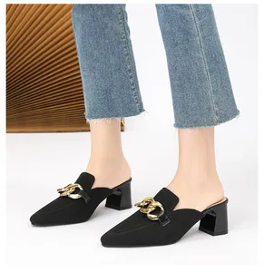 Nahaufnahme von schwarzen Mules mit goldener Kette und Blockabsatz für Damen