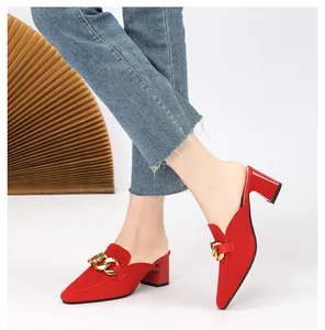 Detailaufnahme von stilvollen roten Strick-Mules mit einer markanten goldenen Kette