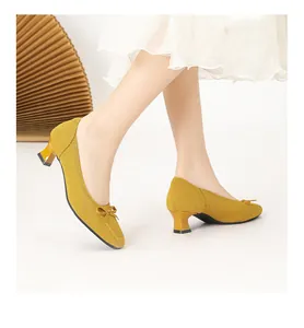Dettaglio di décolleté in maglia giallo senape con punta quadrata e fiocco decorativo