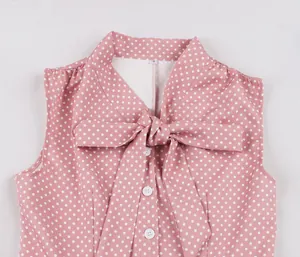 Détail d'une robe sans manches rose à pois blancs avec un nœud élégant au niveau du col