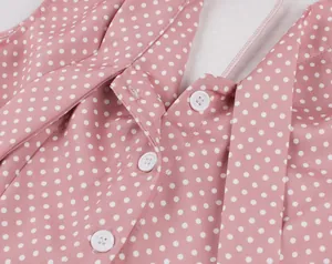 Gros plan d'une robe rétro rose à pois montrant des boutons blancs et l'encolure