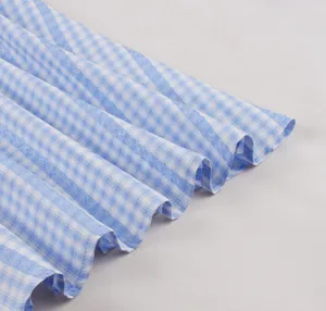 Detailed close-up of blue and white gingham pleated hem on a vintage style summer dress