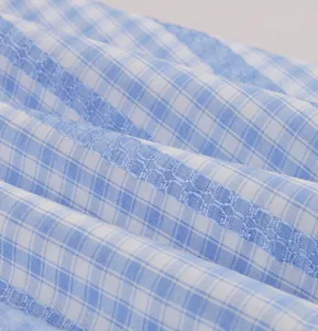 Detailed macro view of light blue and white gingham fabric with intricate lace embroidery