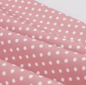 Gros plan détaillé montrant la texture du tissu rose à pois blancs pour robe d'été rétro