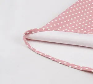 Détail en gros plan des coutures fines et de la doublure blanche d'une robe à pois roses