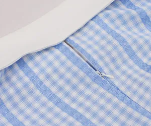Detailed macro shot of an invisible zipper on a blue and white plaid retro dress