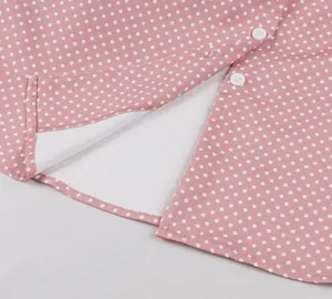 Gros plan détaillé d'une robe rose à pois avec boutons blancs et coutures soignées.