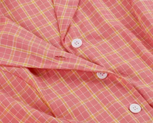 Primer plano de un vestido de cuadros rosa vintage con botones blancos y cuello de solapa