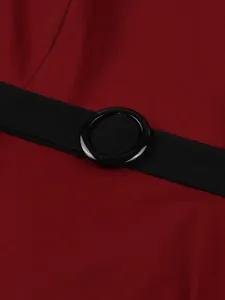 Close-up detail of a circular black belt buckle on a vintage red cotton midi dress