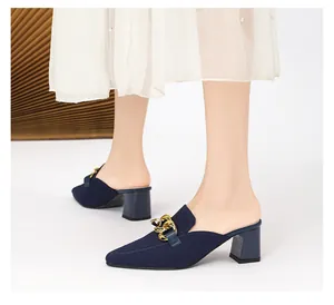 Nahaufnahme eleganter spitzer Mules in Marineblau mit modischer goldener Kettenschnalle.