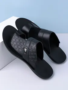 Close-up detail of black men's fashion sandals with textured straps and metal buckle