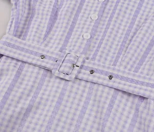 Detail of purple gingham dress featuring white buttons and a matching waist belt.
