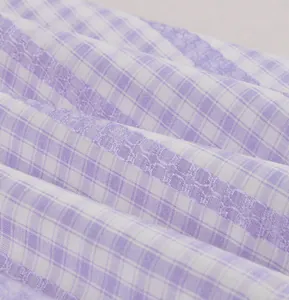 Close-up detail of purple and white plaid fabric with lace inserts for vintage dress