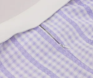 Detailed close-up of the invisible zipper and purple plaid fabric of the retro dress.