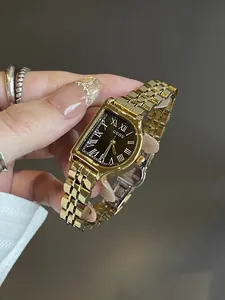 Detalle de un reloj vintage dorado para mujer con números romanos en esfera negra