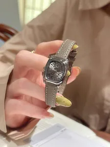 Detalle de primer plano de un reloj cuadrado vintage con esfera de leopardo y correa gris