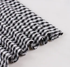 Close-up detail showing the ruffled hem and textured gingham fabric of the dress