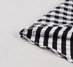 Detail view showing the fine stitching and texture of black and white gingham fabric.