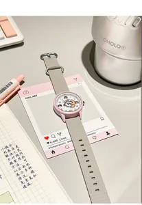 Primer plano de un reloj de cuarzo rosa para estudiantes con esfera de dibujos y correa.
