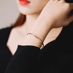 Close-up detail of rose gold bangle with The One and Only engraving on wrist