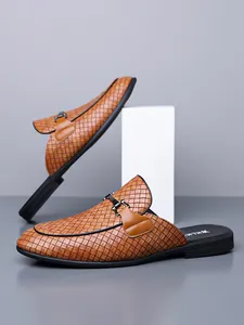 Gedetailleerd macro-zicht op bruine geweven leren loafers zonder hiel met gesp